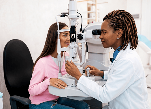 A patient at the slit lamp while the ophthalmologist examines the front of her eye