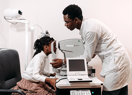 An ophthalmologist guiding a young patient through an examination at the autorefractor